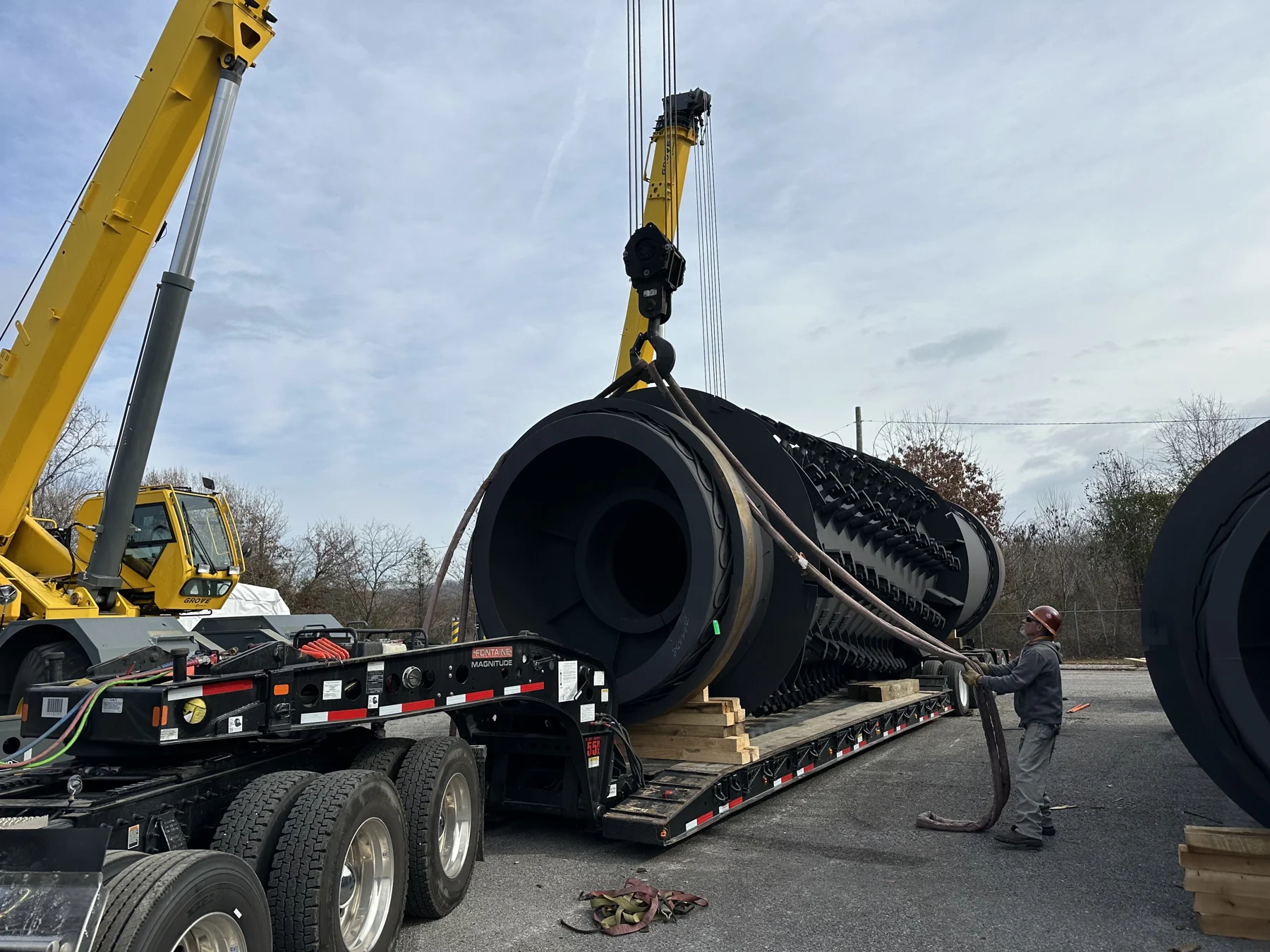 A large industrial component being lowered onto a heavy-haul trailer